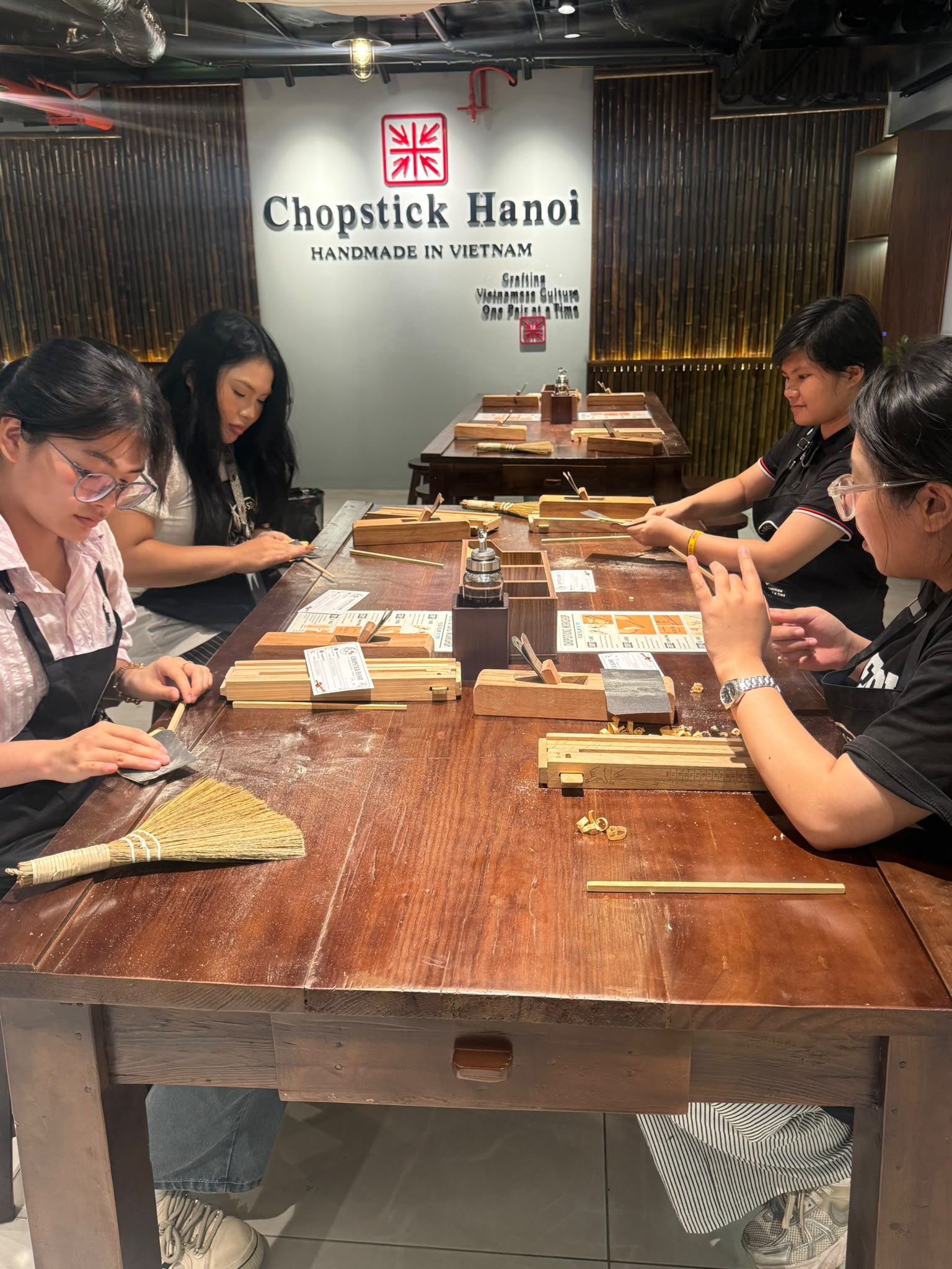 Four people making chopsticks together at Chopstick Hanoi