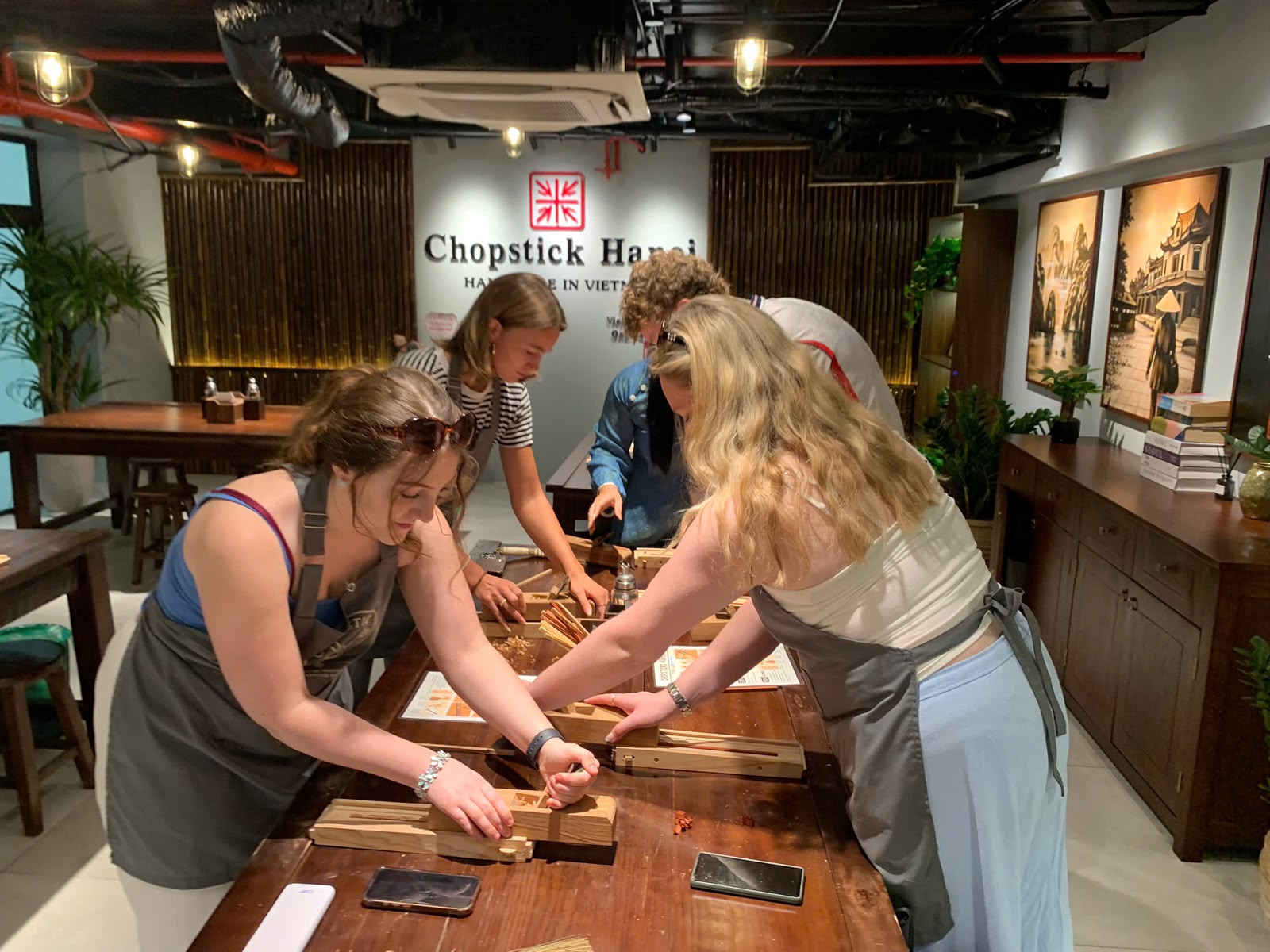 A group of guests shaping chopsticks together at the workshop table