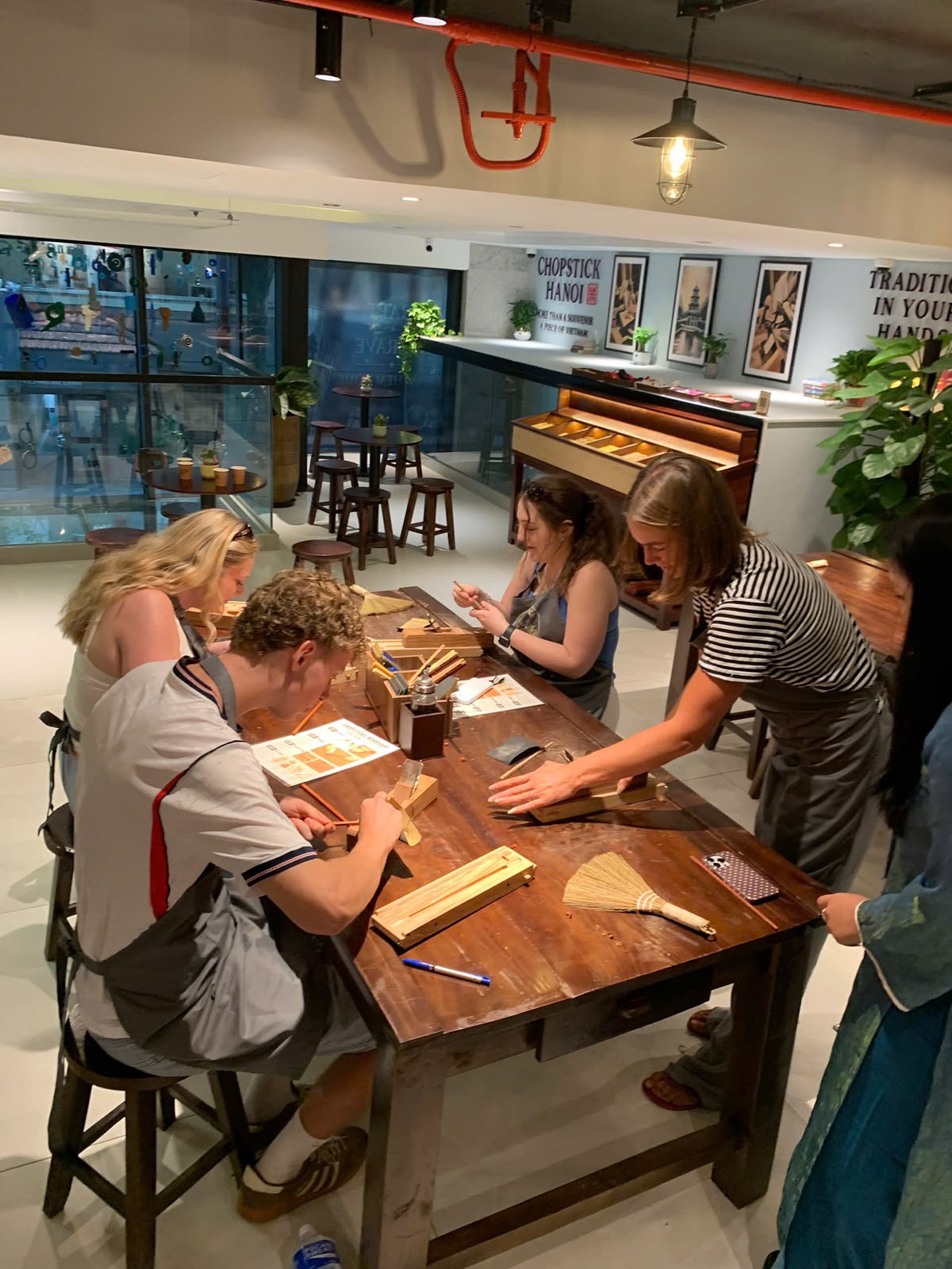 Four guests working on their chopsticks around the workshop table