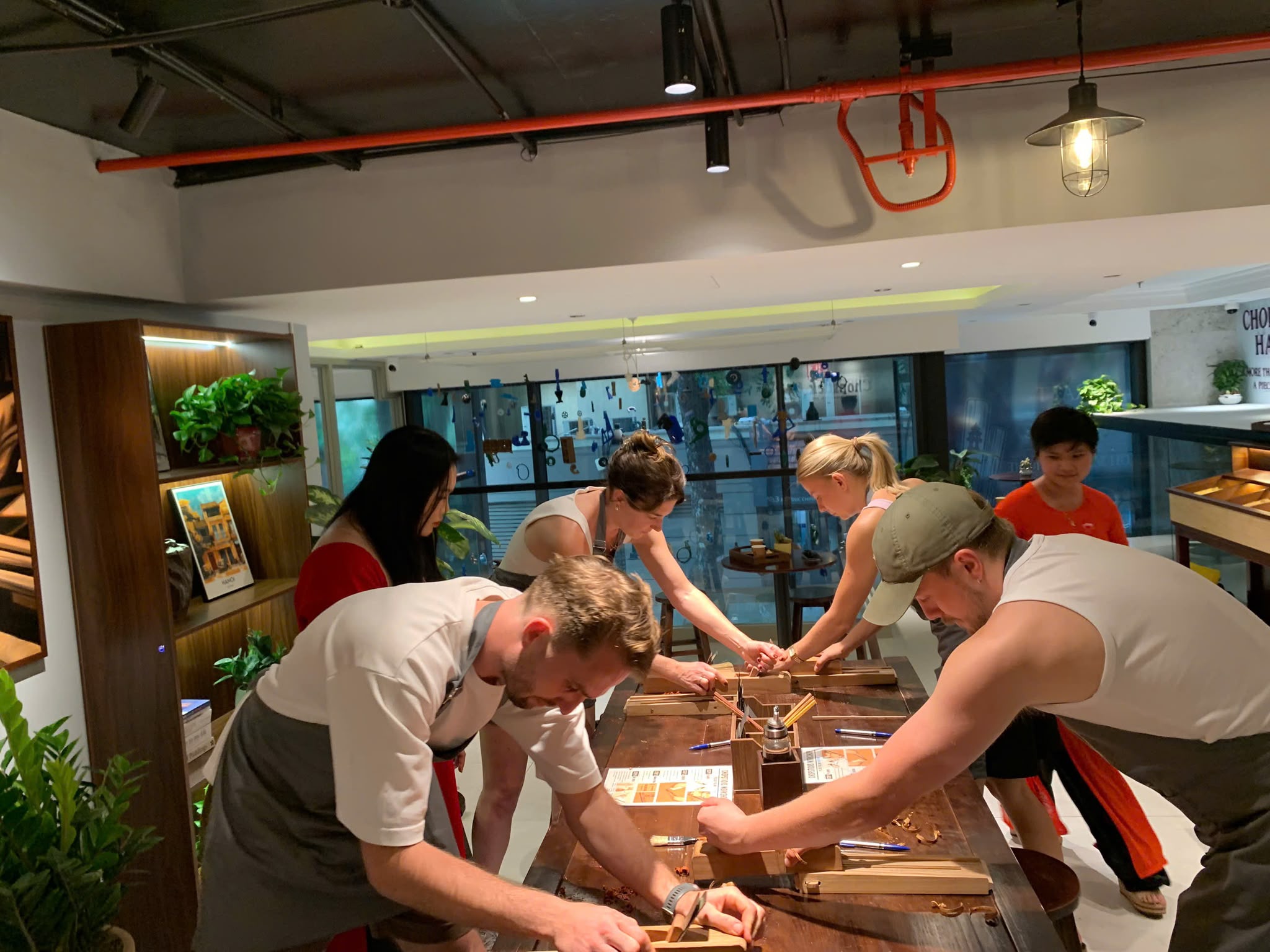 A group of guests shaping wooden chopsticks together at the workshop table
